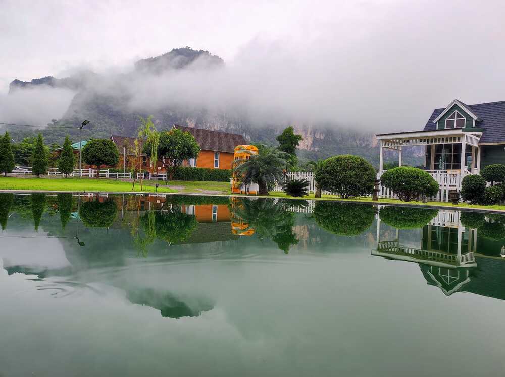 สระน้ำจืดกับที่พักที่มองเห็นพร้อมภูผาม่านและหมอก
