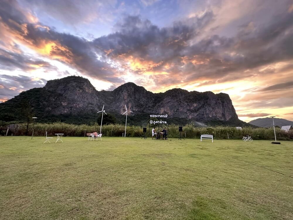 ลานกว้างกางเต้นท์ที่มีคนเล่นดนตรีสดของ หลงเขาคาเฟ่